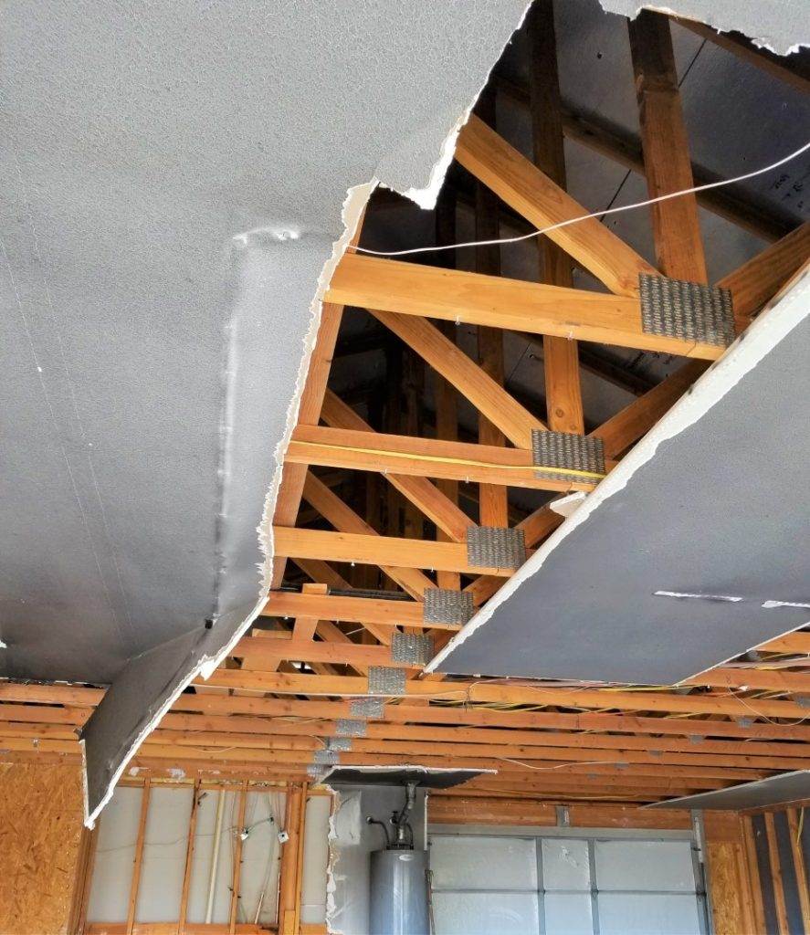 Exposed wooden beams and wiring in a partially demolished ceiling await the skilled touch of American Restoration Contractors.