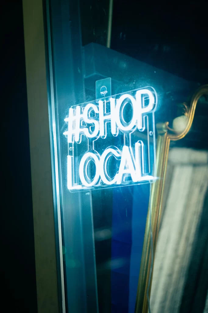A neon sign blazes "#SHOP LOCAL" in bright blue, proudly displayed on a glass surface, much like a local restoration company in Central Florida showcasing its commitment to community revival.